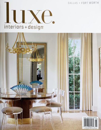 Elegant dining room with modern chandelier and decorative blue centerpieces featured in luxe interiors + design magazine.