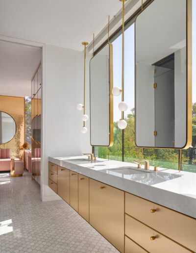 A bright, modern bathroom with a long vanity, dual mirrors, and brass accents.