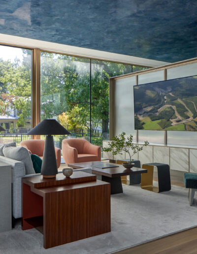 Modern living room with large windows, contemporary furniture, and a landscape painting.