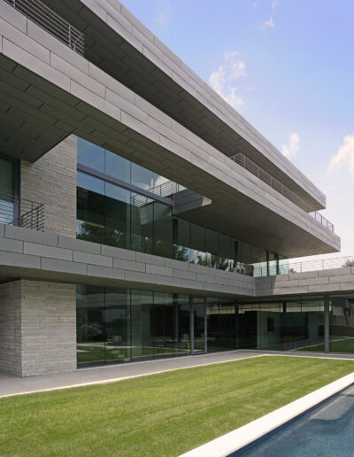 Modern office building with layered terraces and reflective windows, set against a clear sky.