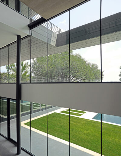Modern office building with glass facade overlooking a courtyard with green lawn.